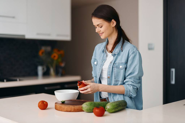 Еда, здоровье и счастье: красивая молодая женщина-повар готовит свежий вегетарианский салат дома. - Фото, изображение