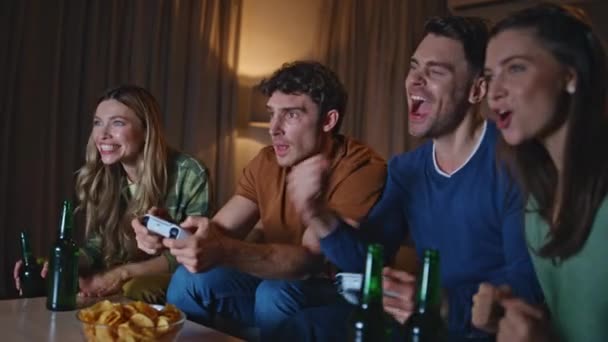 リビングルームのソファーでビデオゲームをプレイする熱狂的なチームが閉じます. 週末に家で集まるコンテストを楽しむ友人たち. 笑顔の勝者は夜のハングアウトで仲間と勝利を喜びます. - 映像、動画