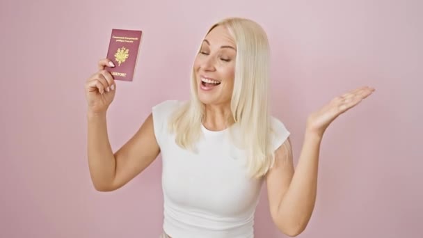 ¡Triunfante victoria! joven, hermosa mujer rubia celebra la aprobación de la visa, alegremente levantando el pasaporte de Francia. desbordamiento de excitación en retrato de fondo rosa aislado. - Imágenes, Vídeo