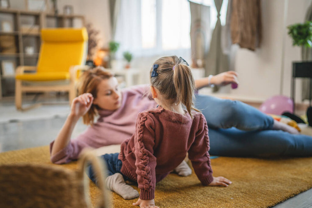 Mutter und Tochter Kleinkind spielen zu Hause im Zimmer auf dem Fußboden - Foto, Bild