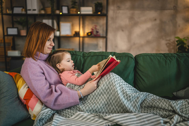 Mother and daughter toddler girl read book at home - Photo, Image