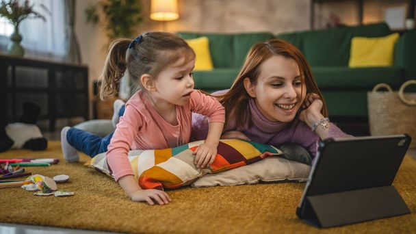 Anne ve kızı evde online video izlemek için dijital tablet kullanıyorlar. - Fotoğraf, Görsel