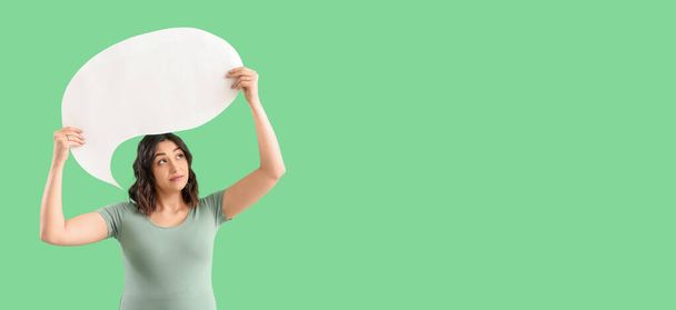 Young pregnant woman holding blank speech bubble on green background with space for text - Photo, Image