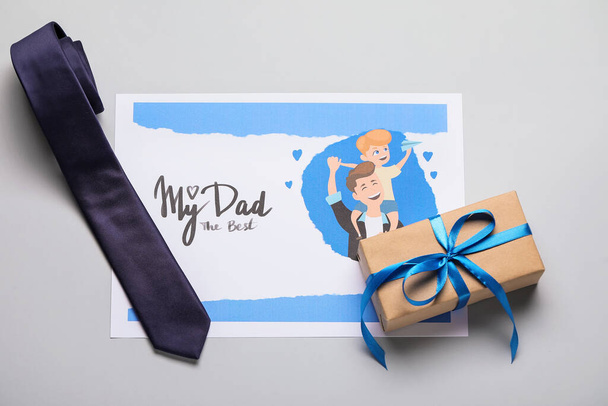 Carte pour la fête des pères avec cadeau et cravate sur fond gris - Photo, image