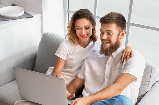 Aşık mutlu çift mutfakta dizüstü bilgisayar kullanıyor. - Fotoğraf, Görsel