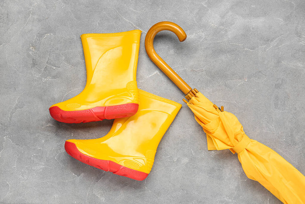 Sárga stílusos esernyő és gumicsizma szürke alapon - Fotó, kép