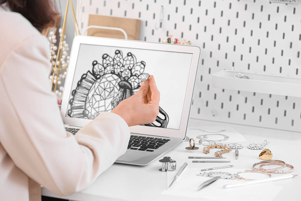 Designer de jóias feminino trabalhando com laptop e esboço de anel no escritório - Foto, Imagem
