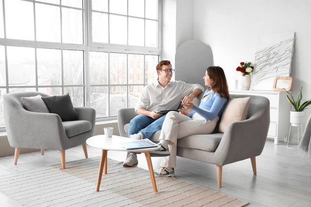 Young couple chatting on grey sofa in living room - Photo, Image