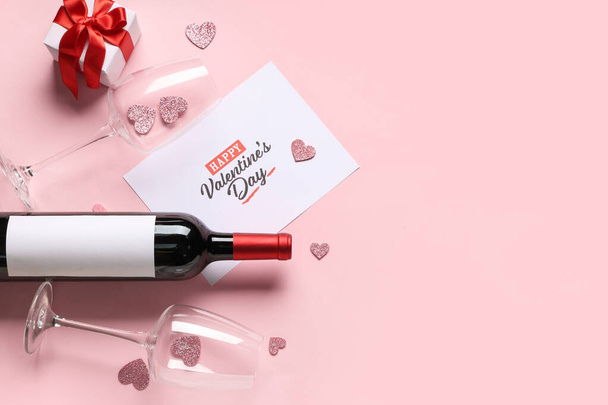 Üzerinde "Mutlu VALENTINE Günü" yazan kart, pembe arka planda bir şişe şarap, bardak ve hediye kutusu - Fotoğraf, Görsel