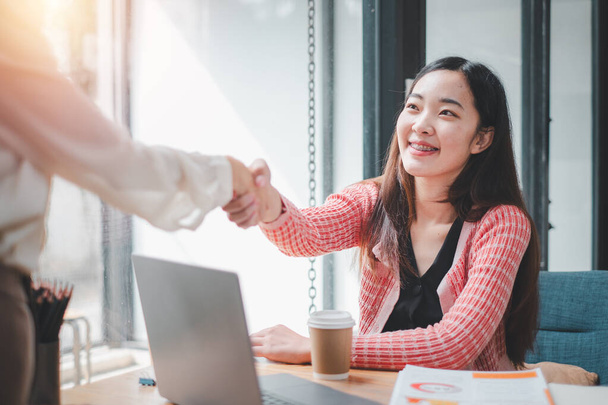 Uma empresária confiante que se envolve em um aperto de mão firme durante uma reunião profissional em um ambiente de escritório ensolarado - Foto, Imagem