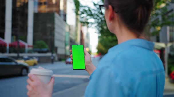 Kobieta stoi na ulicy i używa smartfona z zielonym ekranem. Komunikacja, dzień pracy, pracowite życie. - Materiał filmowy, wideo
