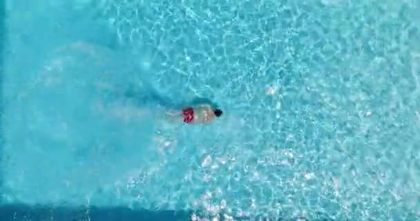 Fentről lefelé, ahogy egy férfi belemerül a medencébe és úszik.. - Felvétel, videó