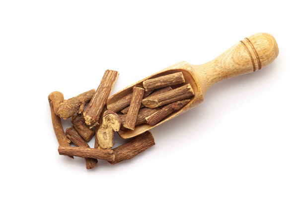 Top view of Dry Organic Liquorice or Mulethi (Glycyrrhiza glabra) roots, in a wooden scoop. Isolated on a white background. - Photo, Image