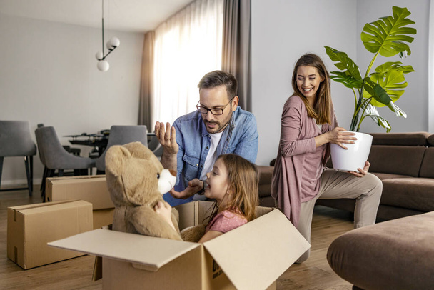 新しいアパートの家で箱と一緒に移動する子供を持つ幸せな家族.新しい家で家族の荷を解く箱. - 写真・画像