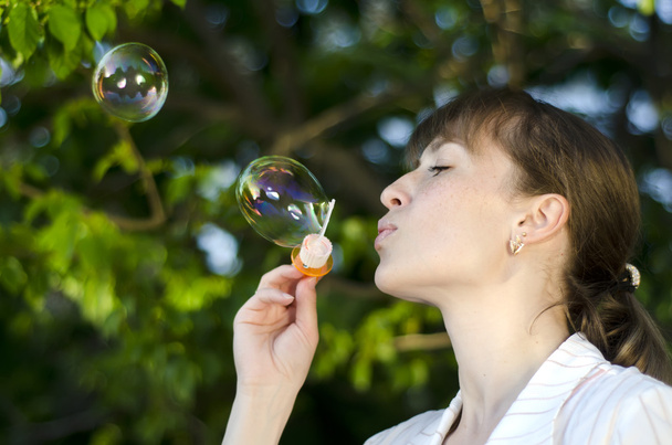 Молодая девушка надувает мыльные пузыри
 - Фото, изображение