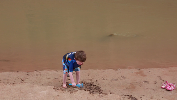 Niño jugando en la orilla del río
 - Metraje, vídeo