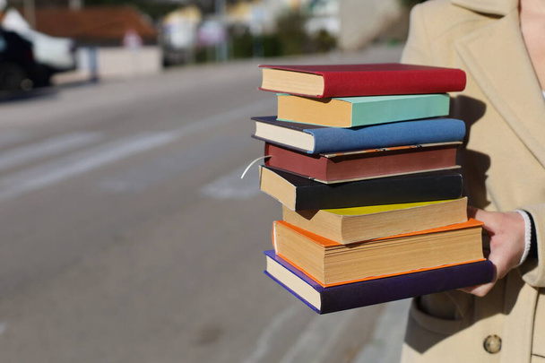 a woman holding a stack of books in her hands - Photo, Image
