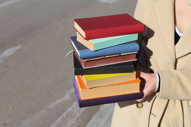 Kobieta trzymająca stos książek w rękach - Zdjęcie, obraz