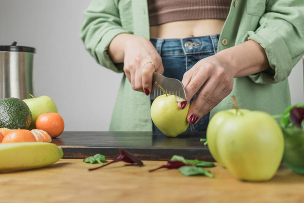 Mulher maçã de corte, preparando smoothie vegan saudável com folhas de espinafre, banana e abacate em uma mesa. - Foto, Imagem