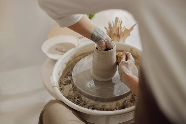Close-up van ambachtslieden handen vormgeven klei kom in aardewerk studio. Aardewerk kunst en creativiteit - Foto, afbeelding
