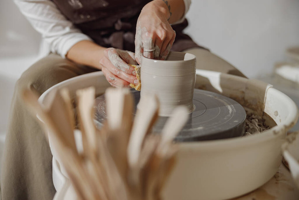 Zbliżenie rzemieślników ręce kształtujące miskę gliny w pracowni garncarskiej. Sztuka garncarska i kreatywność - Zdjęcie, obraz
