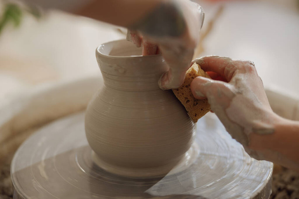 Gros plan des mains d'artisans façonnant un bol d'argile dans un atelier de poterie. Art de la poterie et créativité - Photo, image