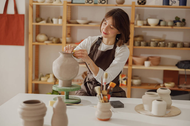 Профессиональная женская керамическая работа с необожженной глиняной вазой в мастерской керамики. Высокое качество фото - Фото, изображение
