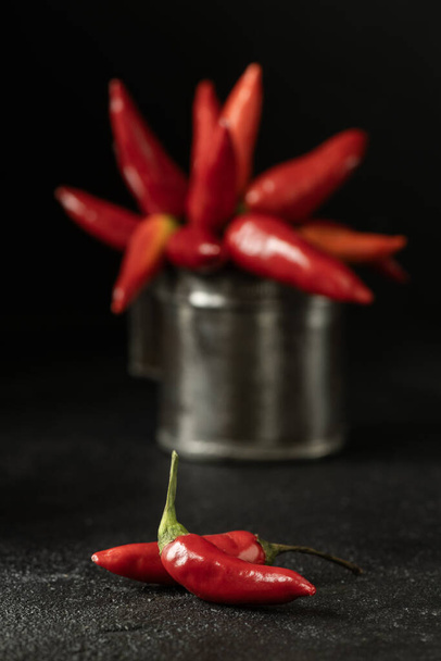 Spicy red chillies in an old metal measuring container on a black background. - Photo, Image