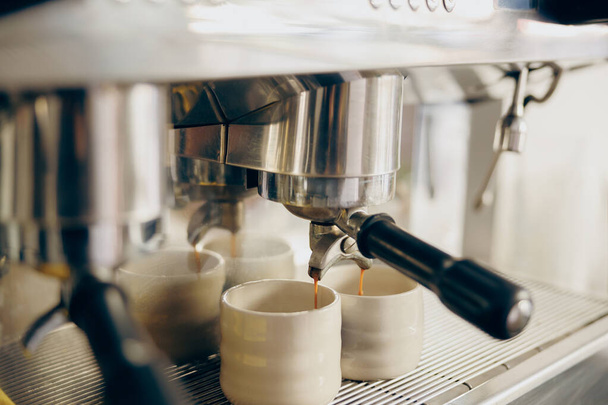 Macchina da caffè che riempie due tazze di caffè espresso in caffetteria professionale. Foto di alta qualità - Foto, immagini