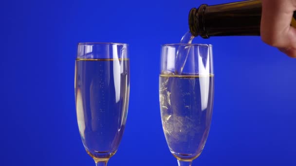 Glasses are filled with champagne on a blue background. Slow motion. - Footage, Video