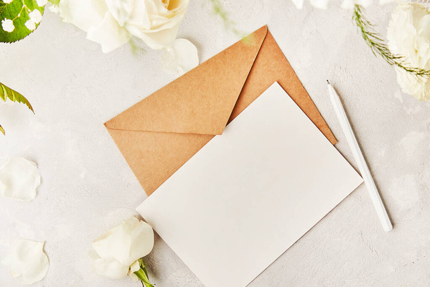 Crafting pastel paper envelope for greetings, invitation, postcard, text among white flowers. Copy space - Photo, Image
