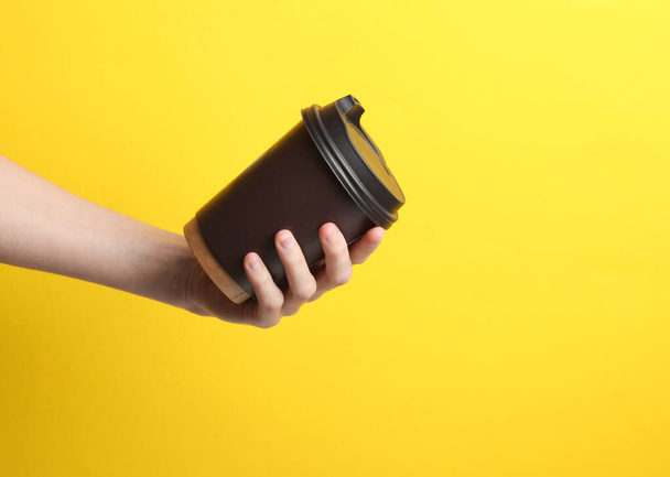 Ręczne gospodarstwa brązowy jednorazowego użytku wyjąć filiżankę na gorące napoje makieta (herbata, kawa) na żółtym tle - Zdjęcie, obraz