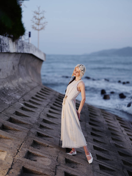 Elegante giovane donna in piedi su una spiaggia di sabbia bianca, sentirsi attraente e rilassato, con il bellissimo oceano blu e il cielo soleggiato come sfondo - Foto, immagini