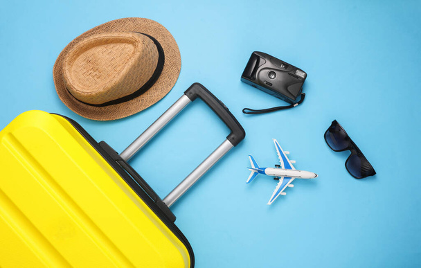 Желтый чемодан, багаж с принадлежностями для путешествий на синем фоне. Летние каникулы, путешествия, концепция поездки. Вид сверху. Плоский лежал - Фото, изображение