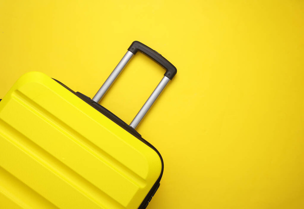 Maleta de ruedas amarillas, bolsa de viaje o equipaje sobre fondo amarillo. Vacaciones de verano, viajes, concepto de viaje. Vista superior - Foto, Imagen