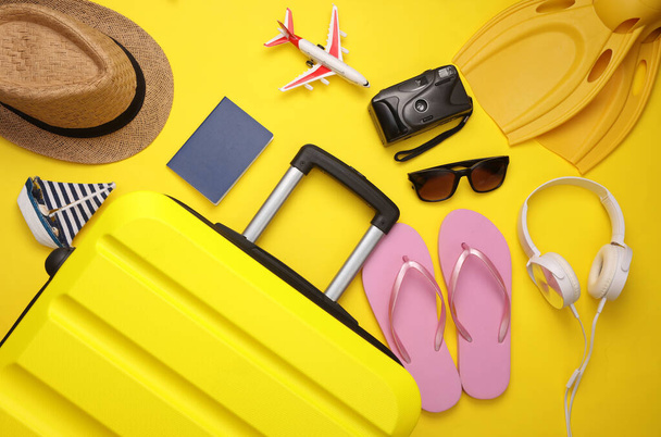 Yellow suitcase, luggage with travel accessories on yellow background. Summer vacation, travel, relocation concept. Top view. Flat lay - Photo, Image