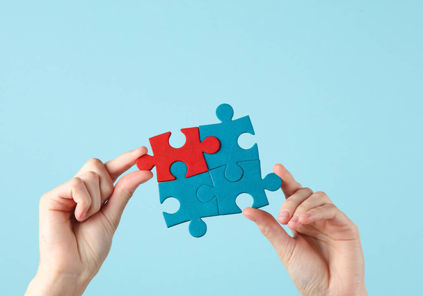 Hands holding puzzle pieces on blue background. Business concept, teamwork - Photo, Image