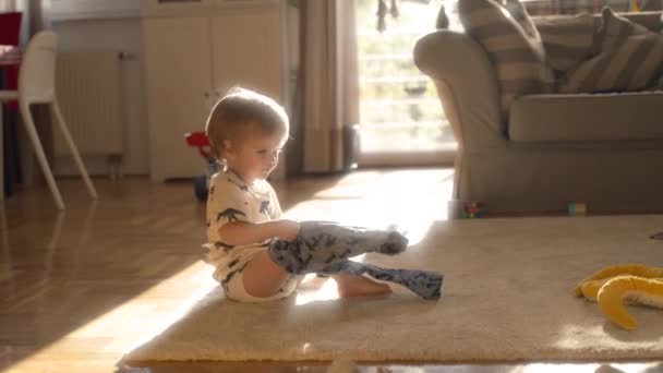 Un bambino si siede sul pavimento, impegnandosi con un serpente giocattolo tenendo, muovendosi ed esplorando le sue caratteristiche.. - Filmati, video