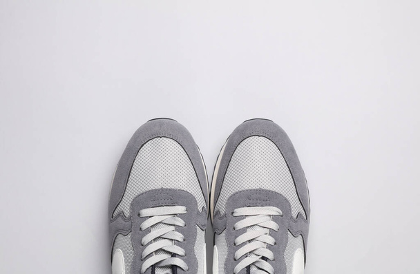 Grijze hardloopschoenen op grijze achtergrond. Casual sneakers. Bovenaanzicht - Foto, afbeelding
