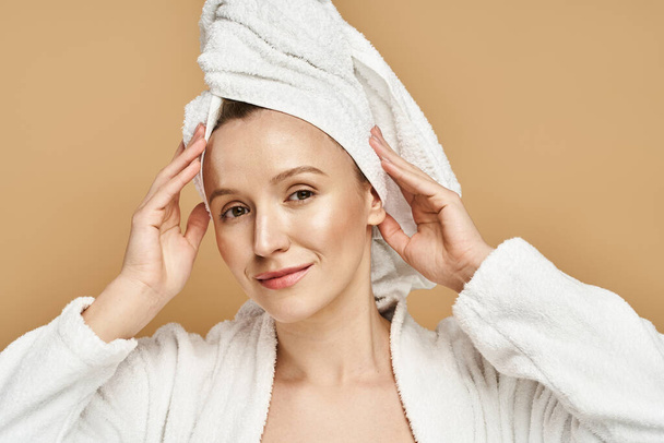 Uma mulher graciosa com uma toalha enrolada em torno de sua cabeça, mostrando beleza natural e rotina de autocuidado. - Foto, Imagem