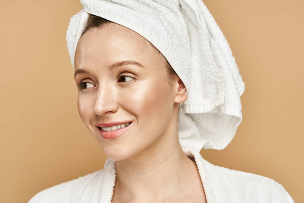 Μια γυναίκα με μια πετσέτα τυλιγμένη γύρω από το κεφάλι της, που ενσωματώνει τη χάρη και τη φυσική ομορφιά σε μια γαλήνια στιγμή. - Φωτογραφία, εικόνα