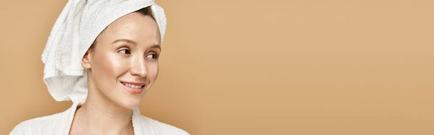 Een mooie vrouw met natuurlijke schoonheid en gratie, poseert zelfverzekerd met een handdoek om haar hoofd. - Foto, afbeelding