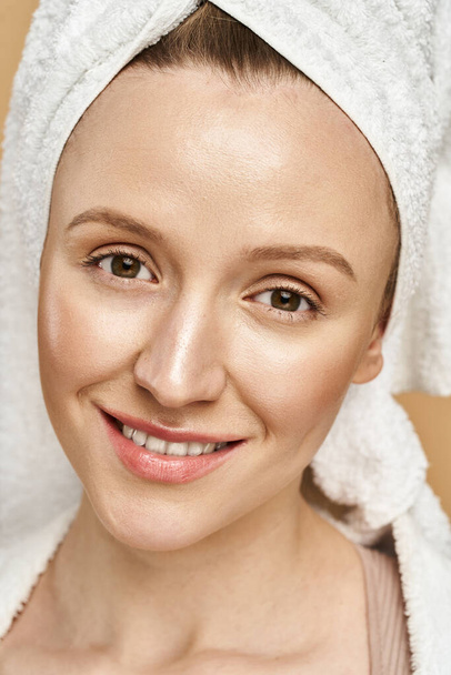 Oszałamiająca kobieta z naturalnym pięknem z wdziękiem pozuje z ręcznikiem owiniętym wokół głowy. - Zdjęcie, obraz