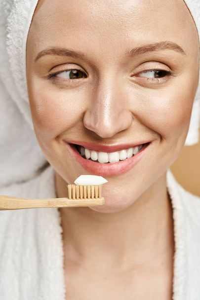 Doğal güzellikte bir kadın, ağzında diş fırçası tutarken kafasında havluyu dengeliyor.. - Fotoğraf, Görsel
