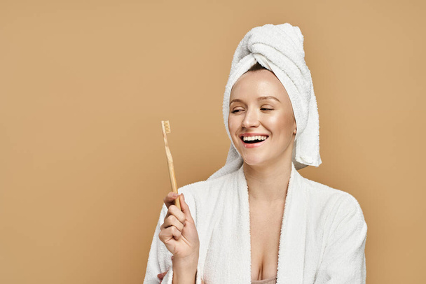 Een sierlijke vrouw met een handdoek om haar hoofd met een tandenborstel.. - Foto, afbeelding