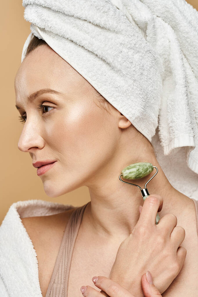 Μια γυναίκα με μια πετσέτα τυλιγμένη γύρω από το κεφάλι της, επιδεικνύοντας φυσική ομορφιά και αυτο-φροντίδα ρουτίνας. - Φωτογραφία, εικόνα