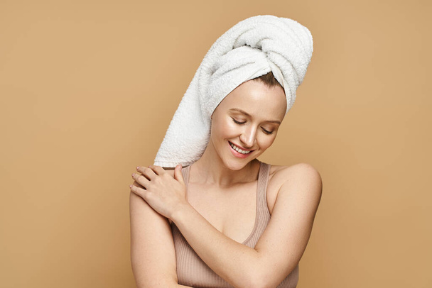 Pełna wdzięku kobieta z ręcznikiem na głowie, ucieleśniająca piękno i samoopiekę w spokojnej chwili. - Zdjęcie, obraz