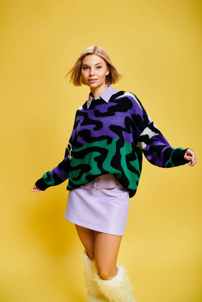 joyful good looking woman with short hair in vibrant sweater posing actively on yellow backdrop - Photo, Image