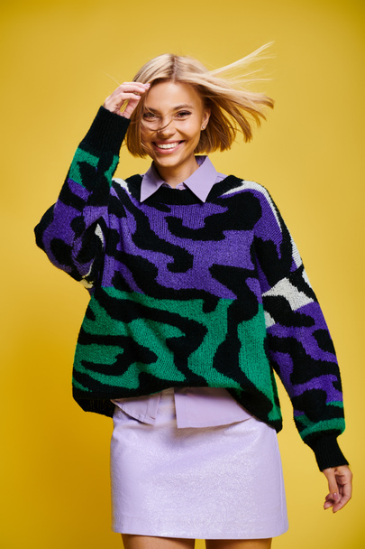 contented good looking woman with short hair in vibrant sweater posing actively on yellow backdrop - Photo, Image