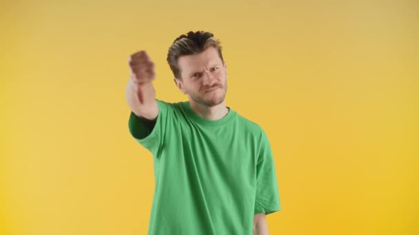 Een man met stoppels staat voor de camera en geeft een duim naar beneden. De man in het groene t-shirt schudt zijn hoofd en geeft een duim naar beneden. Hoge kwaliteit 4k beeldmateriaal - Video
